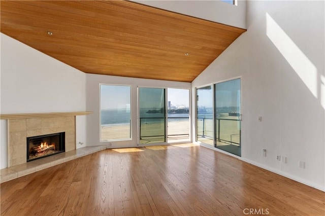 unfurnished living room featuring wood ceiling, a wealth of natural light, a tile fireplace, and wood finished floors