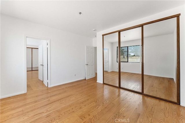 unfurnished bedroom featuring a closet, baseboards, and light wood-type flooring