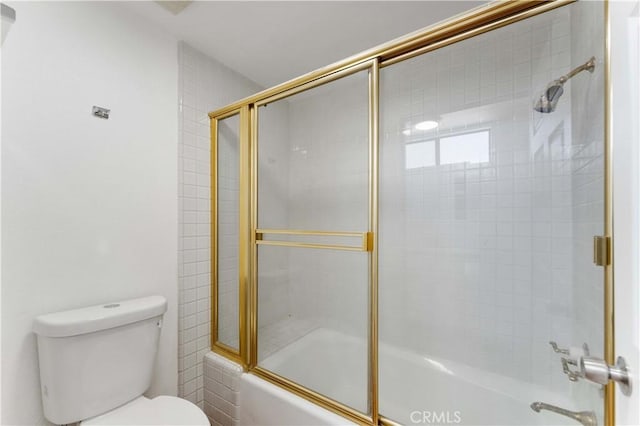 bathroom with combined bath / shower with glass door and toilet