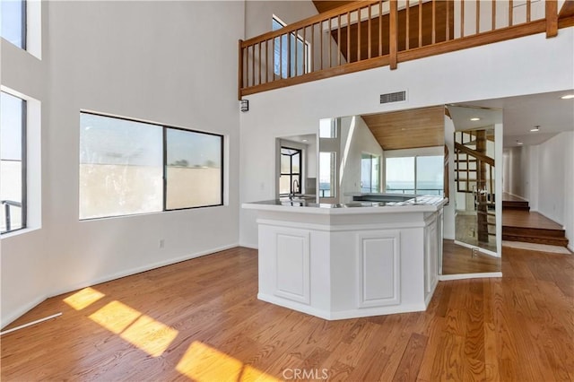 kitchen featuring light wood finished floors, a wealth of natural light, visible vents, and white cabinets