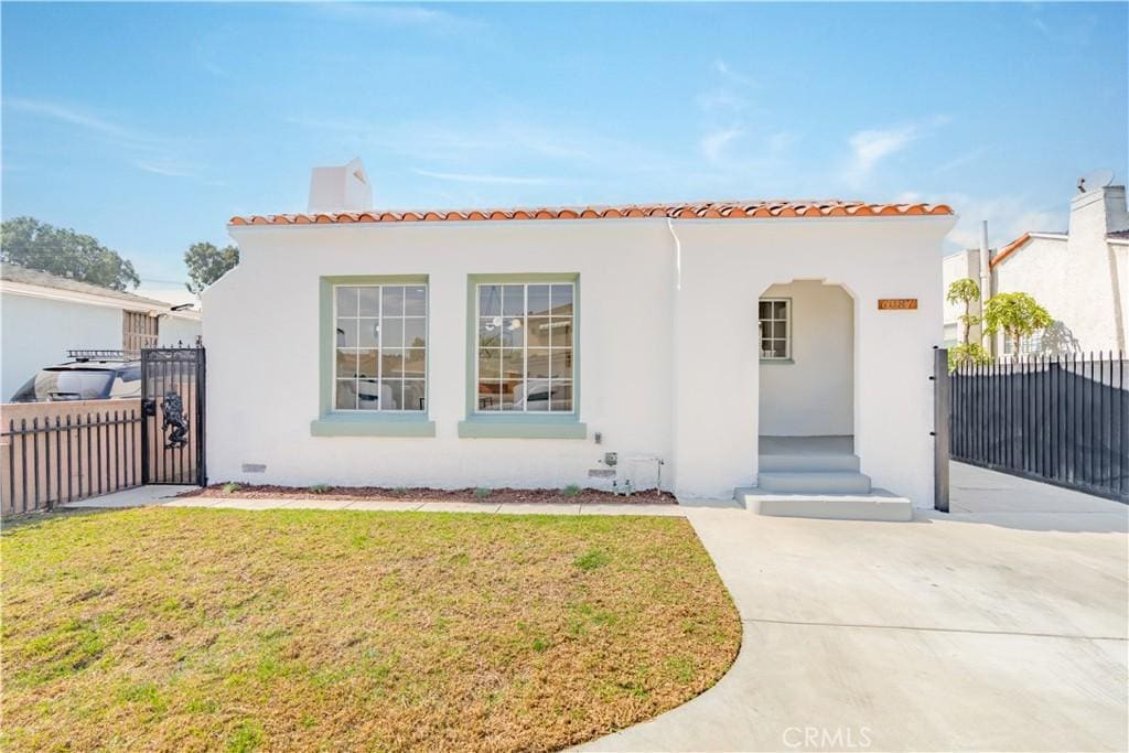 mediterranean / spanish house featuring stucco siding, a gate, fence, and a front yard