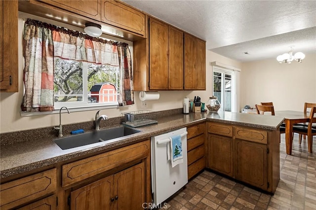 295 Chestnut Ave, Red Bluff, CA 96080 - kitchen with a chandelier, a peninsula, a sink, white dishwasher, and brown cabinetry