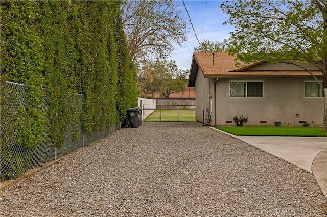 295 Chestnut Ave, Red Bluff, CA 96080 - view of side of property featuring stucco siding, fence, driveway, a gate, and a lawn