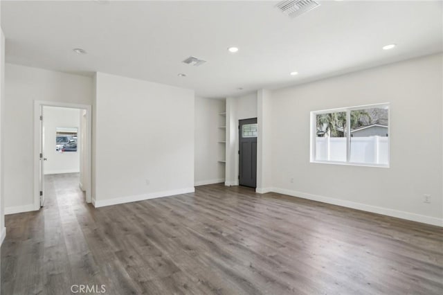 unfurnished living room with wood finished floors, visible vents, recessed lighting, and baseboards