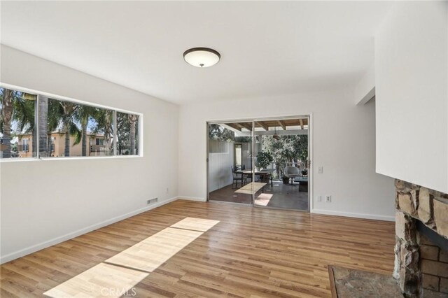 unfurnished living room featuring baseboards, visible vents, wood finished floors, and a fireplace