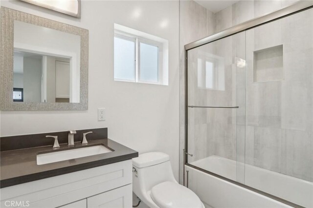 full bathroom featuring toilet, vanity, and combined bath / shower with glass door