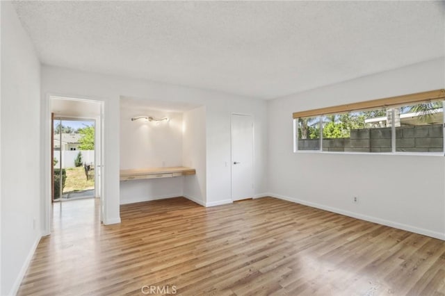 interior space with a textured ceiling, wood finished floors, and baseboards