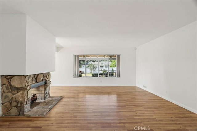 unfurnished living room with a fireplace, wood finished floors, and baseboards