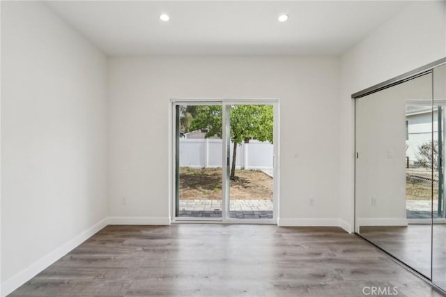 unfurnished room featuring wood finished floors, recessed lighting, and baseboards