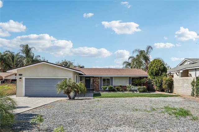 ranch-style house with driveway, an attached garage, fence, and stucco siding