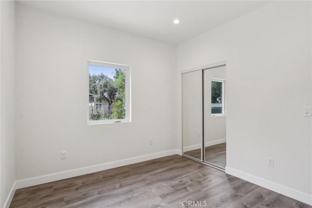 unfurnished bedroom with a closet, wood finished floors, and baseboards