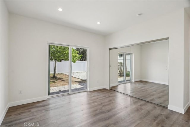 interior space with wood finished floors, recessed lighting, access to outside, and baseboards