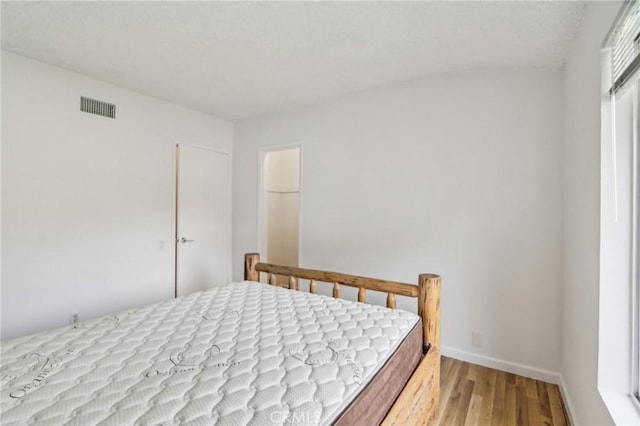bedroom with visible vents, wood finished floors, and baseboards