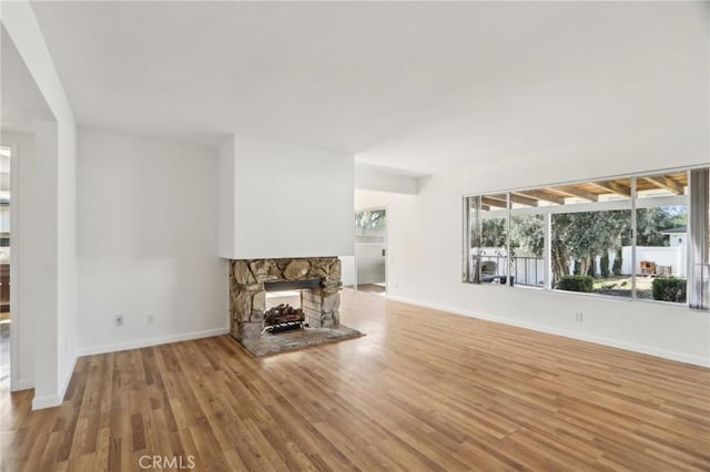 unfurnished living room featuring baseboards, wood finished floors, and a fireplace