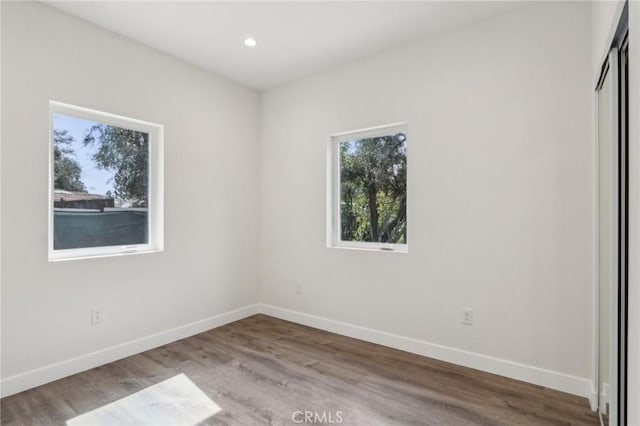 unfurnished room with wood finished floors, plenty of natural light, and baseboards