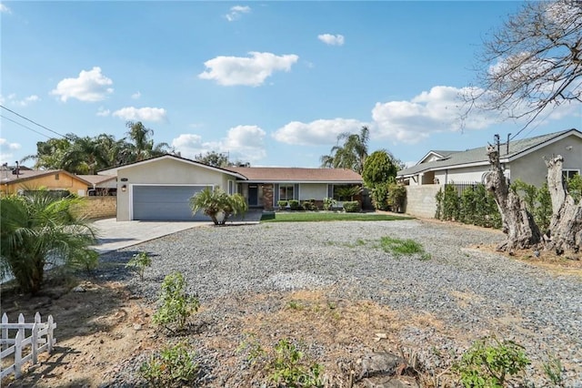single story home featuring fence, gravel driveway, and a garage