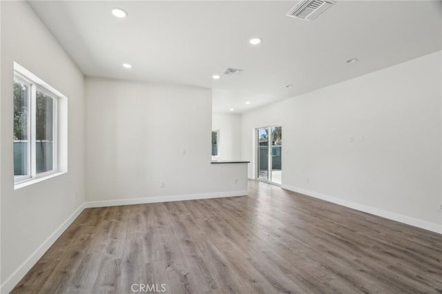 empty room featuring baseboards, visible vents, wood finished floors, and recessed lighting