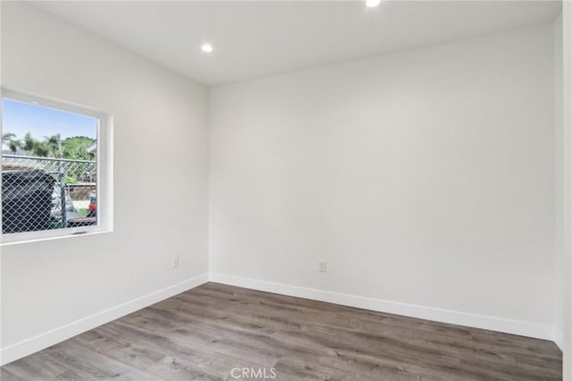 unfurnished room with recessed lighting, wood finished floors, and baseboards