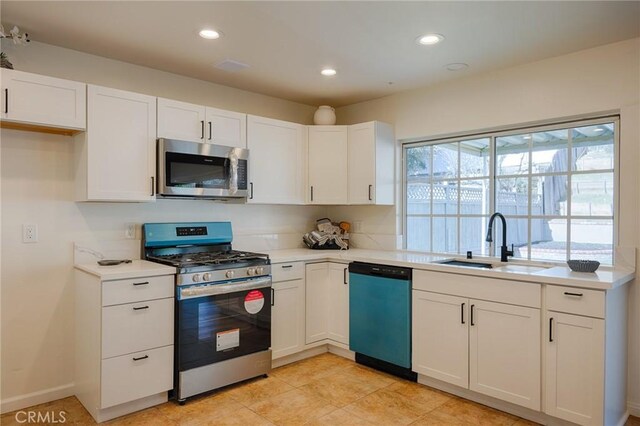 kitchen with light countertops, appliances with stainless steel finishes, a sink, and white cabinetry