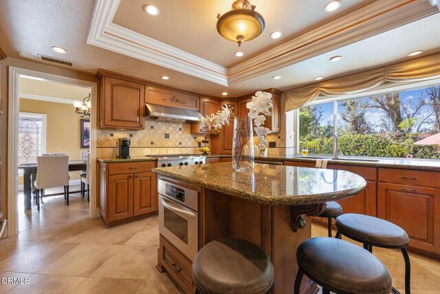 22671 Cheryl Way, Lake Forest, CA 92630 - kitchen with stainless steel oven, crown molding, under cabinet range hood, decorative backsplash, and a center island