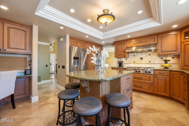 22671 Cheryl Way, Lake Forest, CA 92630 - kitchen featuring under cabinet range hood, a raised ceiling, stainless steel appliances, a breakfast bar area, and a kitchen island