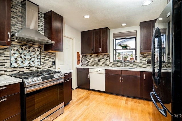 16372 Hollywood Ln, Huntington Beach, CA 92649 - kitchen with dishwasher, stainless steel range with gas stovetop, wall chimney exhaust hood, a sink, and freestanding refrigerator
