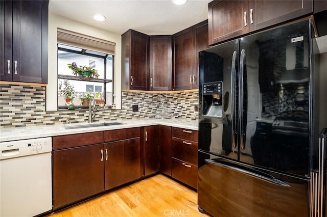 16372 Hollywood Ln, Huntington Beach, CA 92649 - kitchen featuring decorative backsplash, light wood finished floors, dishwasher, a sink, and black fridge