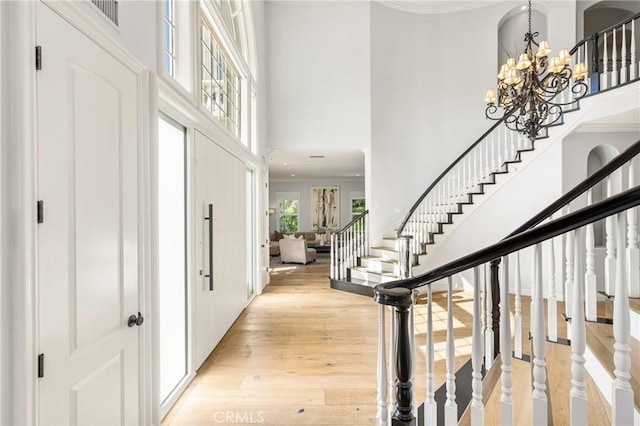 2107 Lemon Heights Dr, Santa Ana, CA 92705 - foyer entrance with a notable chandelier, a towering ceiling, light wood-type flooring, crown molding, and stairs