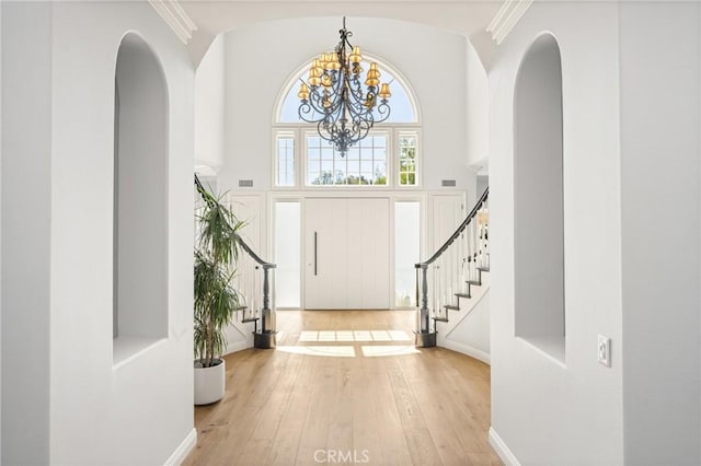 2107 Lemon Heights Dr, Santa Ana, CA 92705 - entryway featuring arched walkways, an inviting chandelier, ornamental molding, stairway, and hardwood / wood-style floors