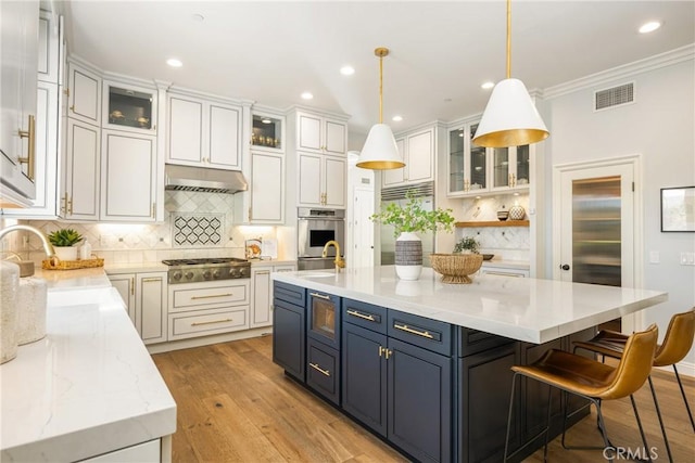 2107 Lemon Heights Dr, Santa Ana, CA 92705 - kitchen with under cabinet range hood, built in appliances, visible vents, and decorative backsplash