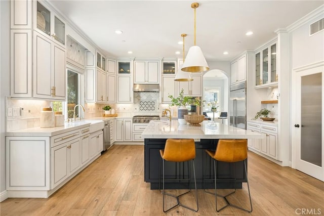 2107 Lemon Heights Dr, Santa Ana, CA 92705 - kitchen with an island with sink, under cabinet range hood, a sink, light countertops, and stainless steel appliances
