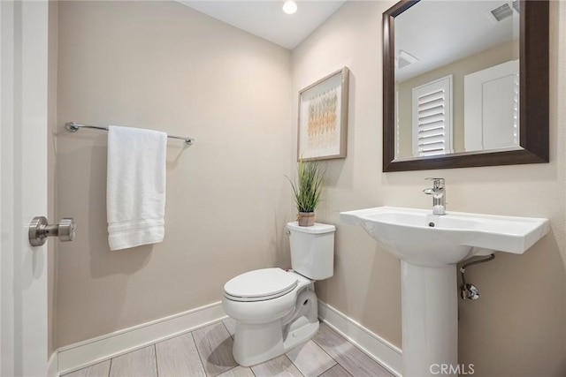 half bath with visible vents, toilet, and baseboards