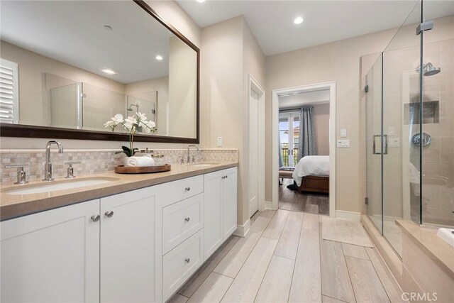 ensuite bathroom with a shower stall, a sink, and backsplash