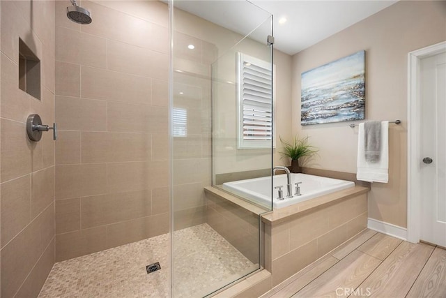 full bath featuring baseboards, a stall shower, wood finished floors, and a garden tub