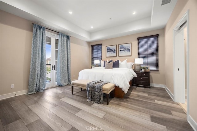 bedroom with a raised ceiling, baseboards, and wood finished floors