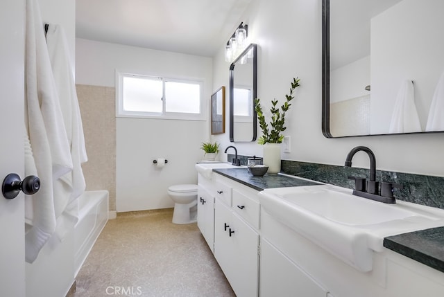 bathroom with toilet, double vanity, and a sink