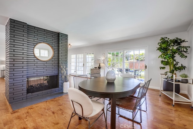dining room with a brick fireplace, wood finished floors, and baseboards
