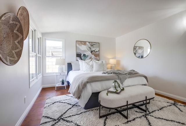bedroom featuring baseboards, wood finished floors, and lofted ceiling