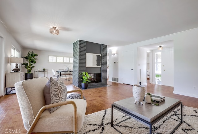 living area with visible vents, baseboards, light wood-type flooring, and a fireplace