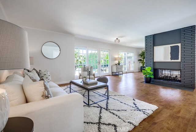 living room featuring wood finished floors, baseboards, and a brick fireplace
