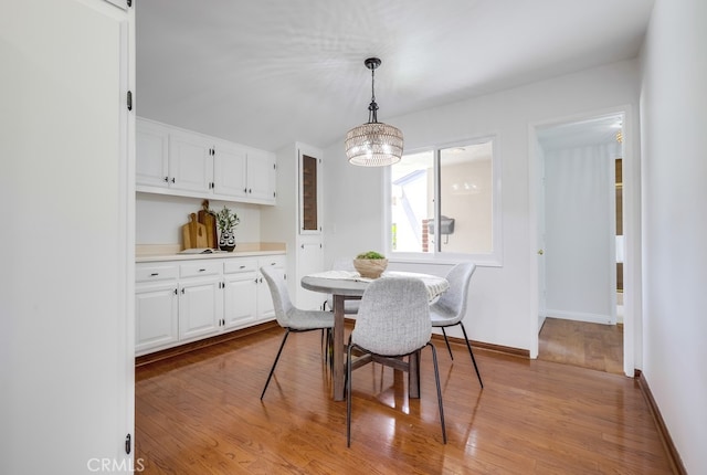 dining room featuring a chandelier, light wood finished floors, and baseboards