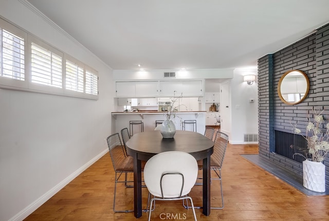 dining area featuring light wood-type flooring, baseboards, ornamental molding, and visible vents