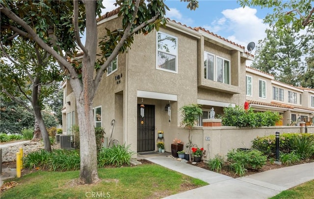 view of property with stucco siding, a tile roof, and fence private yard