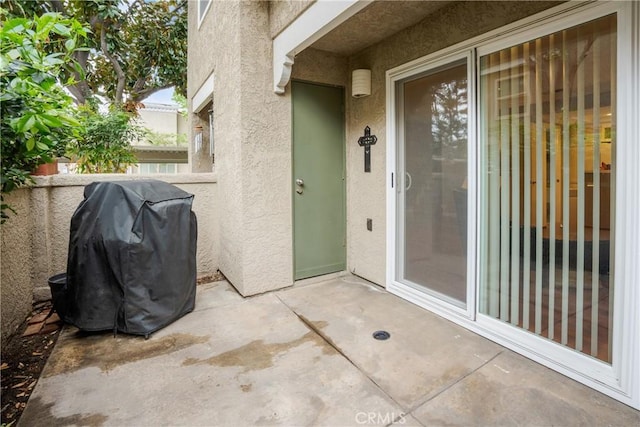 view of exterior entry featuring a patio, stucco siding, and fence