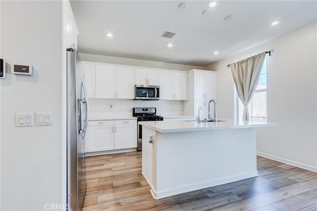 972 W Jasmine Way, Rialto, CA 92376 - kitchen with appliances with stainless steel finishes, light wood-type flooring, white cabinets, light countertops, and a kitchen island with sink