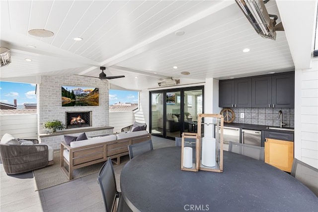 view of patio featuring an outdoor living space with a fireplace, a ceiling fan, and a sink