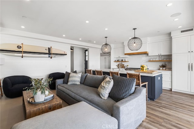 living room featuring light wood finished floors, visible vents, and recessed lighting