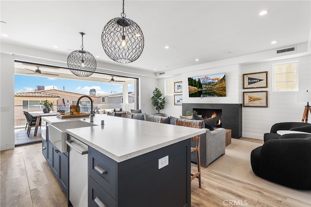 kitchen featuring dishwasher, open floor plan, a sink, and light wood-type flooring
