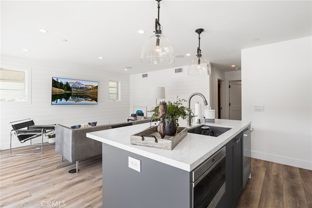 kitchen featuring a sink, light wood-type flooring, a center island with sink, appliances with stainless steel finishes, and visible vents