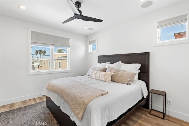 bedroom featuring baseboards, wood finished floors, and multiple windows